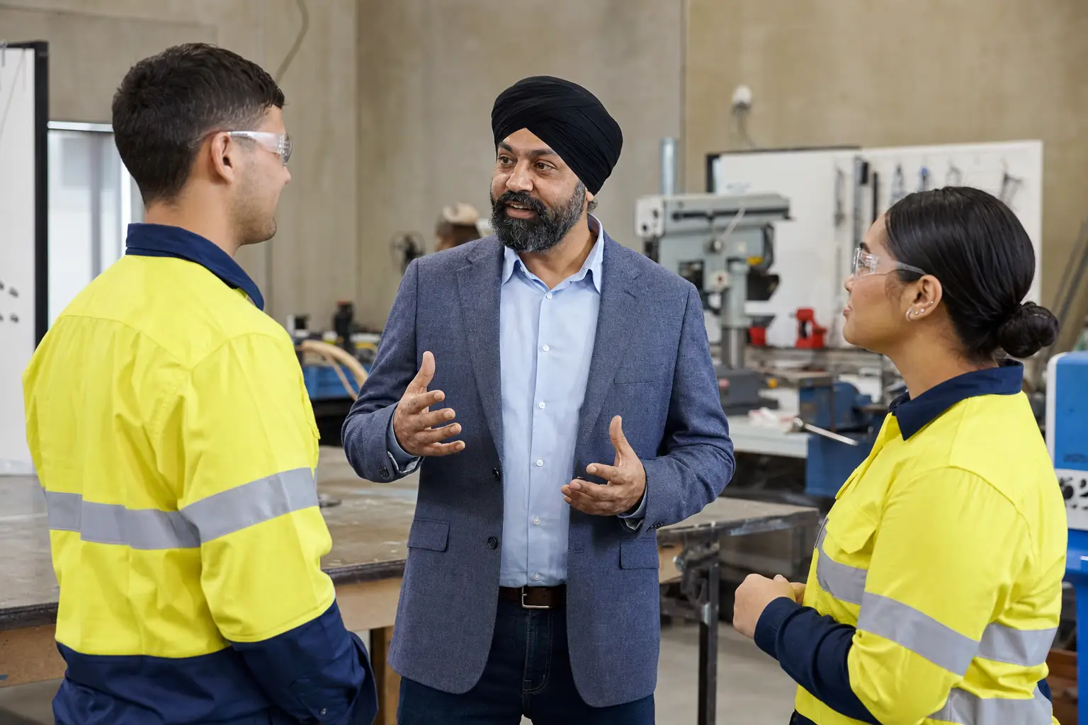 A Punjabi Australian RTO owner talking with two students in a training workshop.